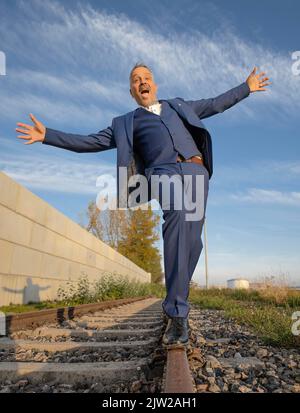 Betrunkener Mann im Anzug balanciert über Bahngleise am Hafen, Rheinhafen, Karlsruhe Stockfoto