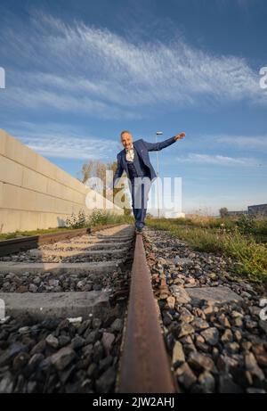 Betrunkener Mann im Anzug balanciert über Bahngleise am Hafen, Rheinhafen, Karlsruhe Stockfoto