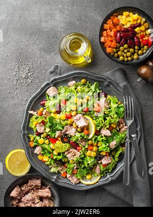 Gesunder grüner Salat mit Thunfisch und Gemüse auf grauem Tischhintergrund. Mexikanischer Maissalat. Stockfoto
