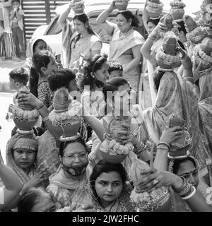 Delhi, Indien April 03 2022 - Frauen mit Kalash am Kopf während des Jagannath-Tempels Mangal Kalash Yatra tragen indische Hindu-Anhänger irdische Töpfe im Container Stockfoto