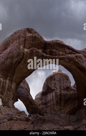 Atemberaubender Blick auf den Arid Arches National Park durch die raue Double Arch Formation an bewölktem Tag in Utah, USA Stockfoto