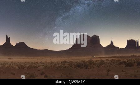 Atemberaubende Aussicht auf die dürde Wüste mit Büschen und unebenen Bergen vor dem Sternenhimmel im Monument Valley National Park in Arizona, USA Stockfoto