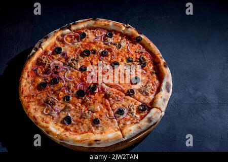 Pizza mit Thunfisch, Oliven, Zwiebeln, Mozzarella-Käse und Tomatensauce auf schwarzem Hintergrund. Draufsicht. Stockfoto