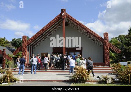 Besucher kommen ins Wharenui (Maori Meeting House), um eine Bühnenshow mit traditionellem Maori-Tanz, Musik und Gesang im Te Puia Whakarewarewa zu sehen Stockfoto