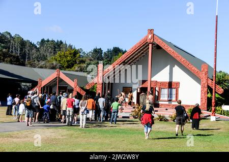 Besucher kommen ins Wharenui (Maori Meeting House), um eine Bühnenshow mit traditionellem Maori-Tanz, Musik und Gesang im Te Puia Whakarewarewa zu sehen Stockfoto