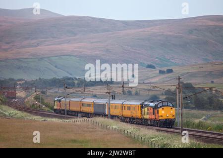 Eine Colas Railfreight Lok der Baureihe 37 37116 auf der Hauptlinie der Westküste in Cumbria mit einem Network Rail Infrastructure Monitoring Zug Stockfoto