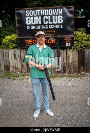 Im Southdown Gun Club & Shooting School in Findon, West Sussex, Großbritannien, steht ein junger Mann mit einer 12-Bohrung über und unter einer Schrotflinte Stockfoto