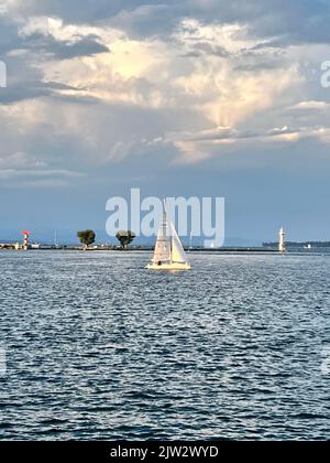 Segelboot, das vor dem Leuchtturm am Genfer See segelt Stockfoto