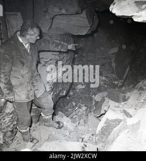 1960s, historisch, ein Mann, der auf den Eingang eines verlassenen, stillgelegten Minenschachts in dem alten Kohlebergbaudorf Townshill, Fife, Schottland, Großbritannien, zeigt. Stockfoto