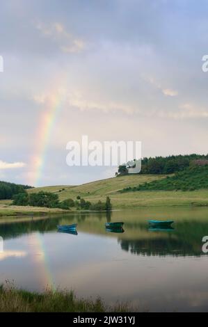 Fischerboote im See bei Dämmerung mit Regenbogen Stockfoto