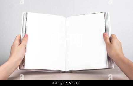 Hände mit offenem Buchmockup mit weißen leeren Seiten. Frau, die Literatur liest. Intellektuelle Entwicklung, Bildung, Informationslernkonzept. Hi Stockfoto