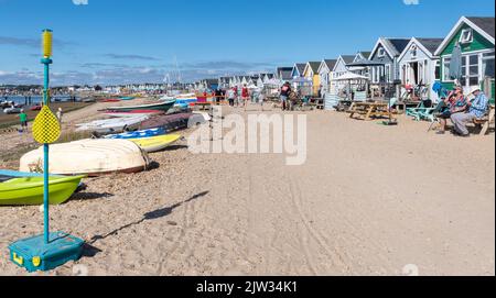 Strandhütten auf der Mudeford Sandbank in der Nähe von Hengistbury Head, Dorset, England, Großbritannien, beschäftigt mit Menschen im Urlaub an einem sonnigen Sommertag Stockfoto