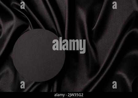 Leere runde Plattform Podium auf schönen schwarzen Hintergrund mit Draperie und welligen Falten aus Seide Satin-Material. Monochromer Hintergrund für Stockfoto