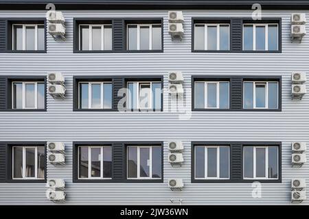 Klimaanlage im Haus. Viele Klimaanlagen hängen an der Fassade des neuen modernen Gebäudes. Die Ventilatoren der zentralen Klimaanlage sind ordentlich an der Außenwand angeordnet Stockfoto