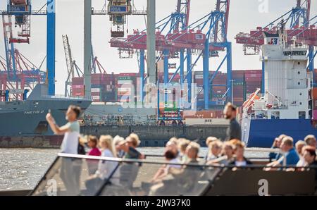 03. September 2022, Hamburg: Die Menschen genießen die Sonne und den Blick auf den Containerhafen mit seinen Kränen auf dem Deck eines Passagierschiffes am Neumühlener Steg (Övelgönne/Museumshafen). Foto: Georg Wendt/dpa Stockfoto