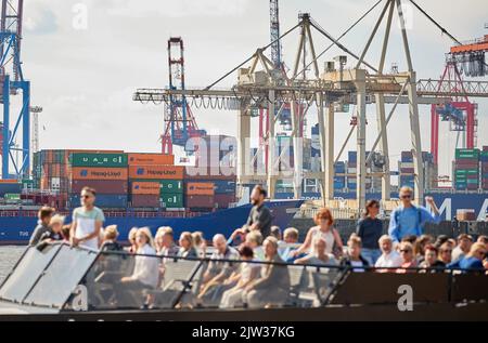 03. September 2022, Hamburg: Die Menschen genießen die Sonne und den Blick auf den Containerhafen mit seinen Kränen auf dem Deck eines Passagierschiffes am Neumühlener Steg (Övelgönne/Museumshafen). Foto: Georg Wendt/dpa Stockfoto