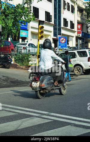 Indischer Mann, der auf der Straße Scooter reitet. Stockfoto