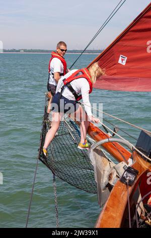 Zwei Crew-Mitglieder arbeiten am Bugsprit des traditionellen Gaffelschneiders „Jolie Brise“ in Solent, Hampshire, Großbritannien Stockfoto