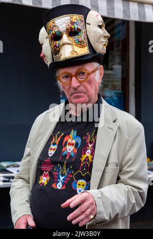 Bridport, Dorset, Großbritannien. 3.. September 2022. Eine Vielzahl von Stil und schrulligen Hüten, die von Menschen und Hunden beim Bridport hat Festival in Dorset hergestellt und getragen werden. Mann mit Hut und venezianischen Masken. Quelle: Carolyn Jenkins/Alamy Live News Stockfoto