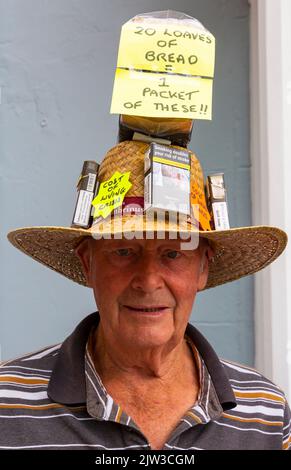 Bridport, Dorset, Großbritannien. 3.. September 2022. Eine Vielzahl von Stil und schrulligen Hüten, die von Menschen und Hunden beim Bridport hat Festival in Dorset hergestellt und getragen werden. Der Mann trägt den Lebenshaltungskosten-Krisenhut und vergleicht den Preis von Broten mit Zigarettenschachteln. Quelle: Carolyn Jenkins/Alamy Live News Stockfoto