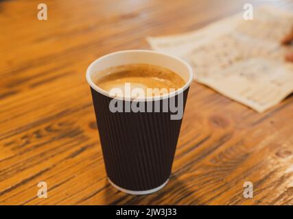 Kleine Einweg-Kaffeebecher mit 90 ml Inhalt für Espresso auf Holztischplatte Stockfoto