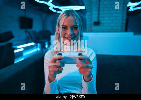 Die Blondine spielt eine Konsole. Stockfoto