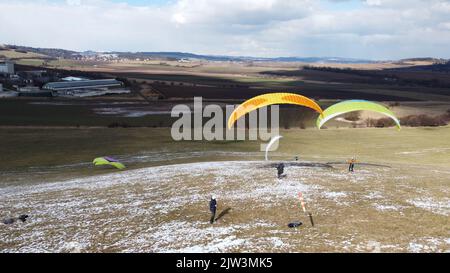 Gleitschirmfliegen und Bodenabfertigungstraining auf der Wiese von Bykovice, Tschechien, Europäische union, Luftpanorama-Aufnahme mit DJI-Drohne im Winter Stockfoto