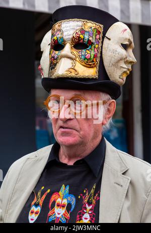 Bridport, Dorset, Großbritannien. 3.. September 2022. Eine Vielzahl von Stil und schrulligen Hüten, die von Menschen und Hunden beim Bridport hat Festival in Dorset hergestellt und getragen werden. Mann mit Hut und venezianischen Masken. Quelle: Carolyn Jenkins/Alamy Live News Stockfoto