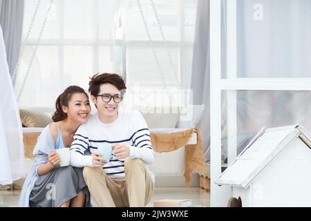 Glückliches junges vietnamesisches Paar in Liebe trinkt Kaffee zu Hause Stockfoto