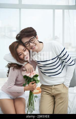 Glücklich umarmt junges Paar in der Liebe mit Blumenstrauß Stockfoto