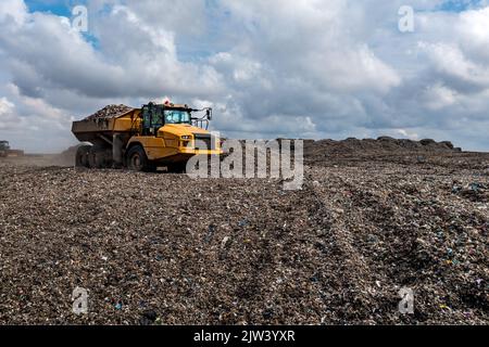 Ein Müllwagen auf einer großen Mülldeponie, der Müll in ein Umweltbild einschleuste Stockfoto