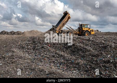 Ein Müllwagen auf einer großen Mülldeponie, der Müll in ein Umweltbild einschleuste Stockfoto