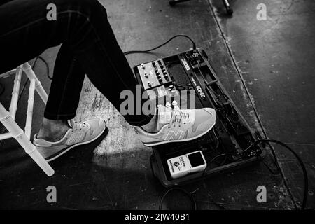 Lviv, Ukraine - Mai, 2021: Foot Wearing New Balance Sneaker drücken auf Effekteinheiten für Gitarre auf der Konzertbühne Stockfoto