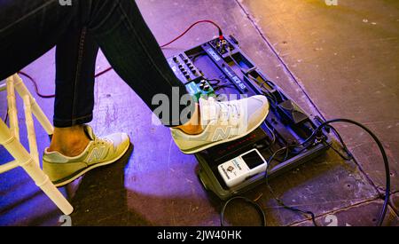 Lviv, Ukraine - Mai, 2021: Foot Wearing New Balance Sneaker drücken auf Effekteinheiten für Gitarre auf der Konzertbühne Stockfoto