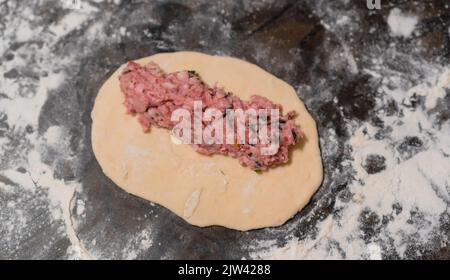 Rohes Hackfleisch auf einem Stück Teig. Halbzeuge. Kochen. Nahaufnahme Stockfoto