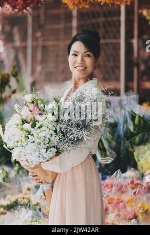 Lächelnd hübsche asiatische Frau mit schönen Blumen Stockfoto