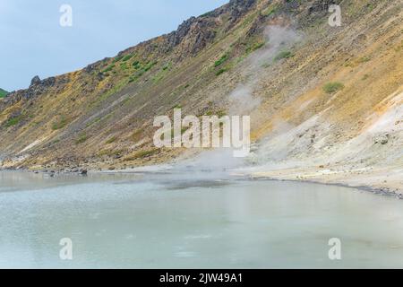 Heißer mineralisierter See mit Thermalquelle und rauchenden Fumarolen in der Caldera des Vulkans Golovnin auf der Insel Kunashir Stockfoto