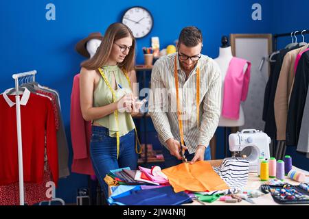 Mann und Frau Schneiderei Schneidertuch Schreiben auf Notebook in der Bekleidungsfabrik Stockfoto