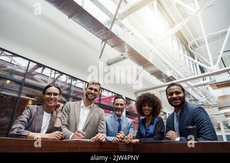Eine Gruppe von glücklichen, motivierten Geschäftsleuten, die im Büro mit ihrem Vorgesetzten zusammenstehen Stockfoto