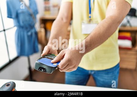 Ladenbesitzer, der im Bekleidungsgeschäft mit dem dataphone und der Kreditkarte den Kauf verlädt. Stockfoto