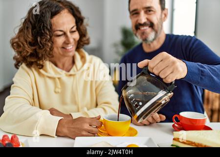 Das hispanische Paar mittleren Alters lächelte fröhlich auf dem Tisch beim Frühstück zu Hause. Stockfoto
