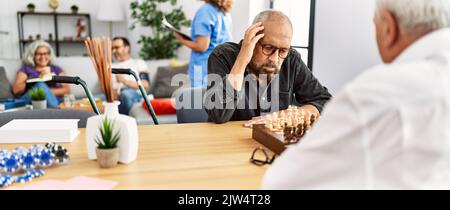 Zwei pensionierte Männer konzentrieren sich auf das Schachspiel im Heim der Krankenschwester. Stockfoto