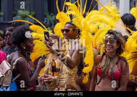 London, England, Großbritannien - 29. August 2022: Junge Leute, die für den Karneval mit Federn in verschiedenen Farben auf den Straßen in Notting Hill gekleidet sind Stockfoto