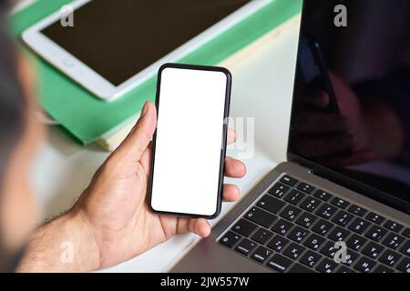 Geschäftsmann, der bei der Arbeit ein Mobiltelefon mit einem weißen Bildschirm hält. Stockfoto