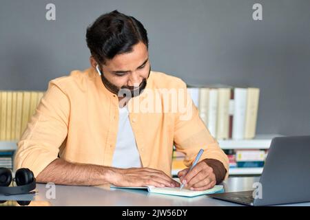 Indischer Geschäftsmann schreibt Notizen während des online-Webinars zum elearning-Kurs. Stockfoto