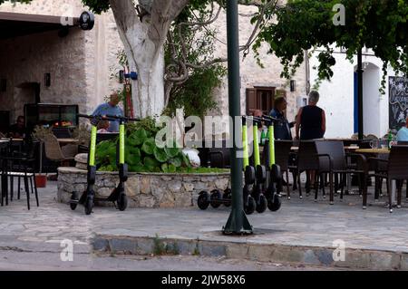 Elektroroller mieten, Dorfplatz, Livadia. Tilos, Dodekanes, Griechenland, EU. Escooter. Stockfoto