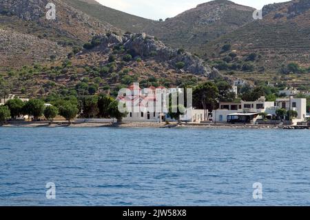 Die Kirche des Heiligen Nikolaus, Agios Nikolaos und das Dorf Livadia, Tilos, von einem Boot aus gesehen. Dodekanesische Inseln, südliche Ägäis, Griechenland Stockfoto