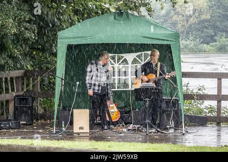 Kidderminster, Großbritannien. 3.. September 2022. Britisches Wetter: Scharfe und schwere Regenschauer trafen heute die Midlands, aber wenn Darsteller eine Aufführung für wohltätige Zwecke in einem lokalen Landschaftspark versprochen haben, geht die Show immer noch weiter. Graham und Bobby sind hier, um den Klassiker von Everly Brothers „Crying in the Rain“ zu erleben, während sich der Himmel öffnet! Kredit: Lee Hudson/Alamy Live Nachrichten Stockfoto