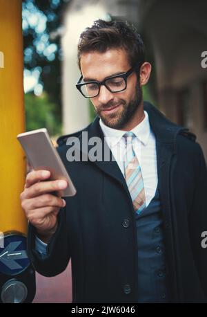 Ein stilvoller Mann, der sein Telefon in der Stadt benutzt. Stockfoto