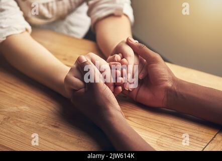 Du bist sicher bei mir. Zwei unkenntliche Menschen halten die Hände in Trost. Stockfoto